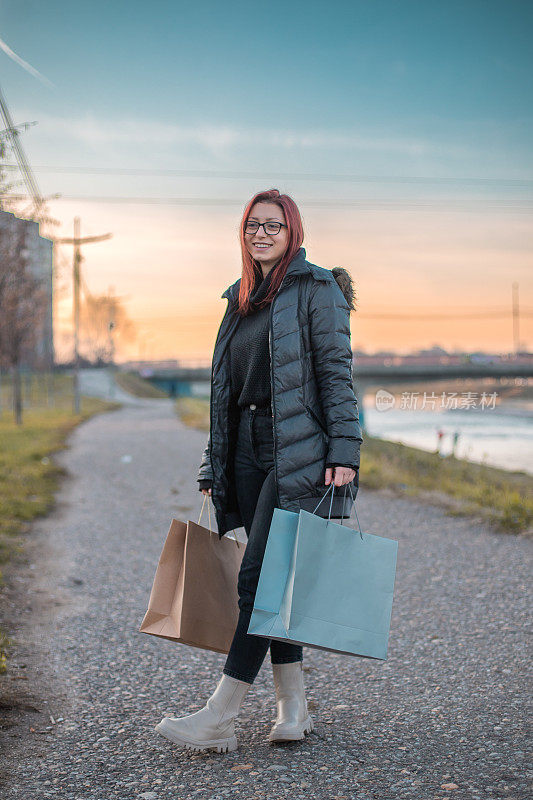 Young woman carrying shopping bags, she is looking at something